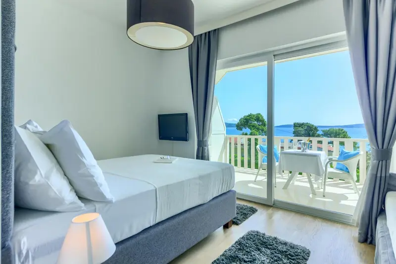 Une chambre lumineuse s'ouvre sur une terrasse avec vue sur la mer.