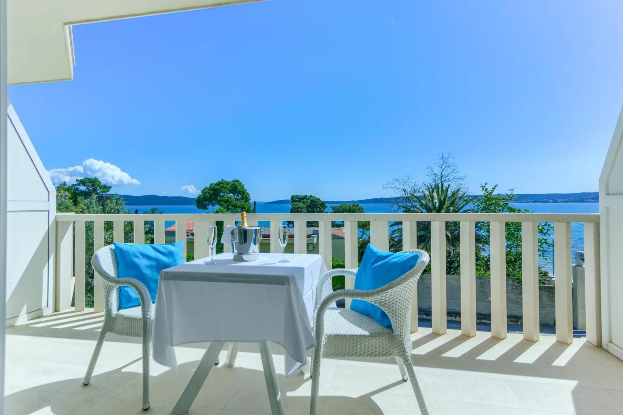 Une table avec des chaises sur une terrasse ensoleillée offre une vue sur la mer.