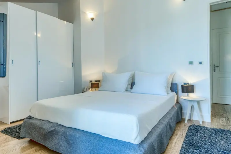 Une chambre lumineuse avec un grand lit recouvert de linge blanc.