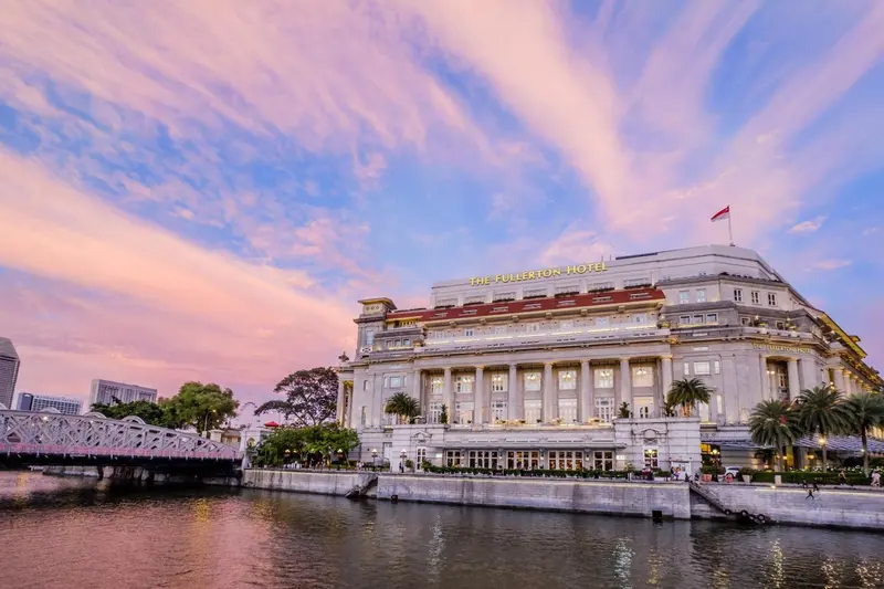 Bâtiment historique au bord de l'eau sous un ciel nuageux au coucher du soleil.