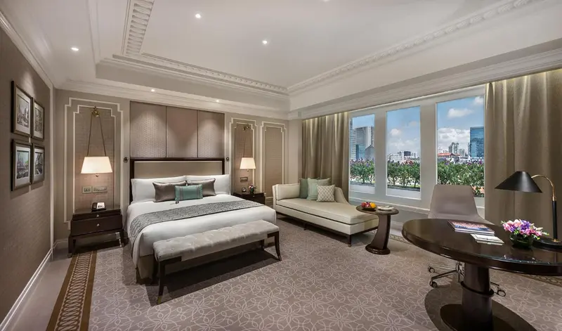 Chambre spacieuse avec un grand lit et un coin salon près d'une fenêtre.