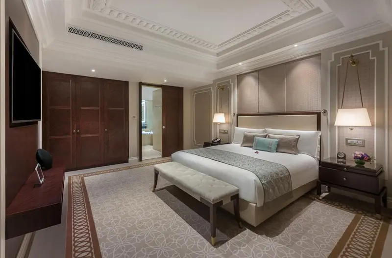 Une chambre d'hotel luxueuse avec un grand lit et un banc au pied du lit.