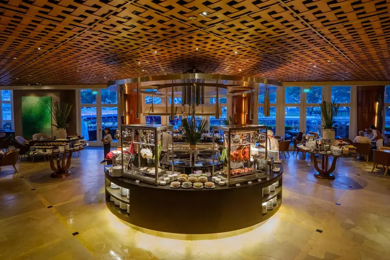 Une salle de restaurant spacieuse avec un buffet central et des tables disposées autour.