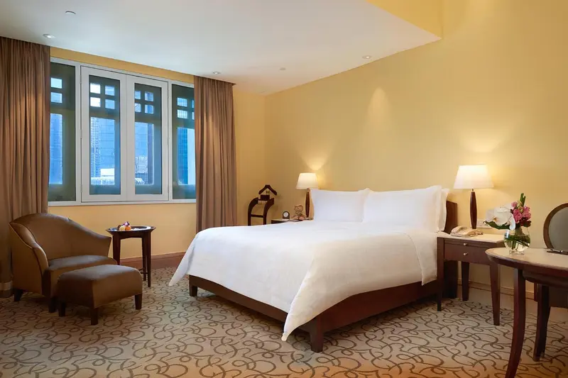Une chambre lumineuse avec un lit double et un fauteuil.