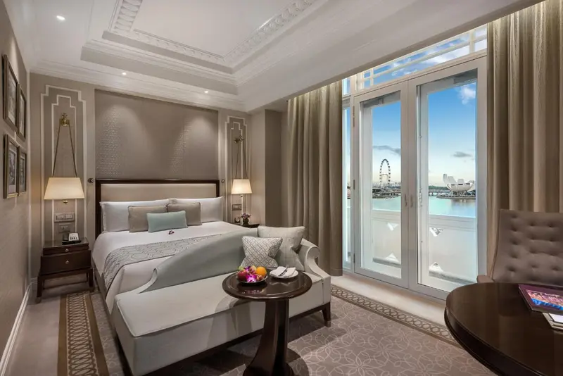 Chambre avec un grand lit et une vue sur la mer à travers de larges baies vitrées.