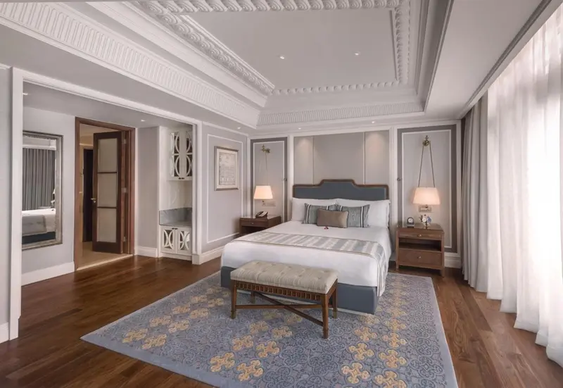 Une chambre spacieuse avec un grand lit et un banc au pied du lit.