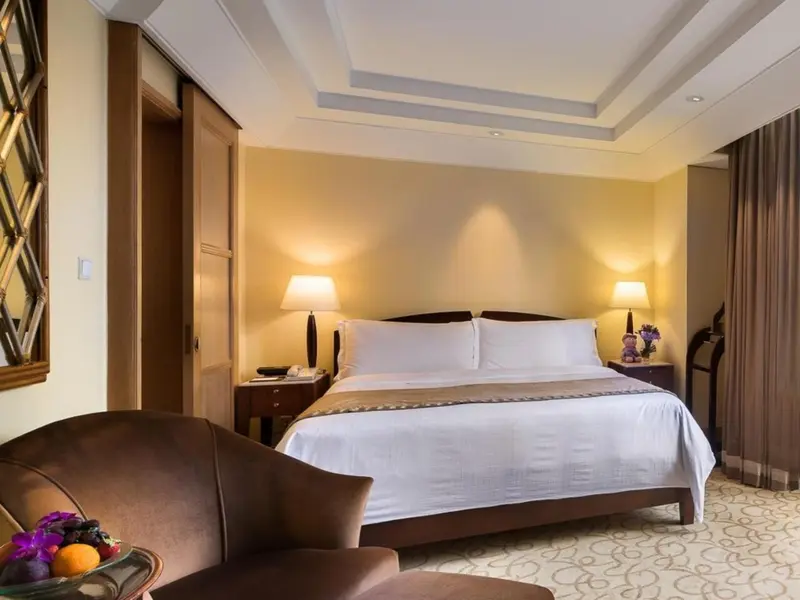 Une chambre lumineuse avec un grand lit et un fauteuil.