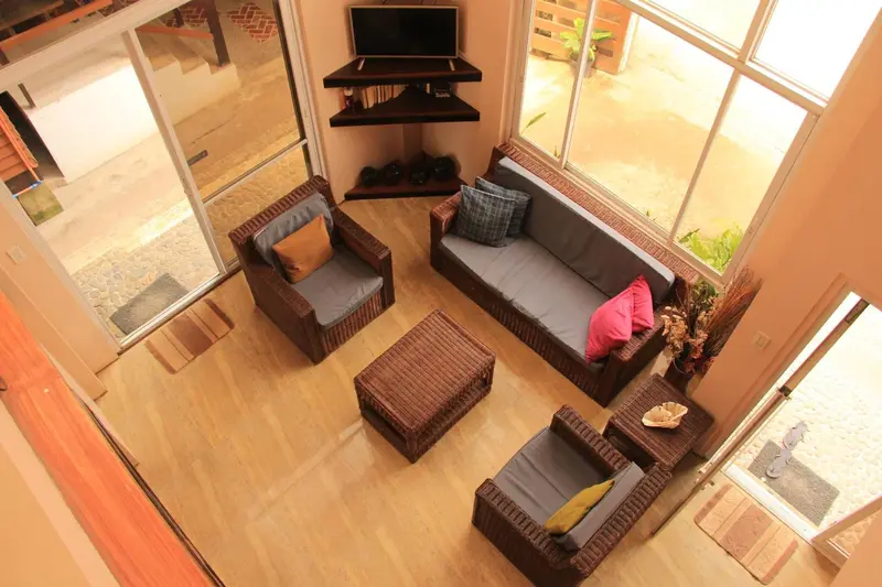 Espace de détente intérieur avec canapés et mobilier en rotin.