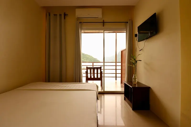 Une chambre lumineuse avec un lit simple et un accès à un balcon.