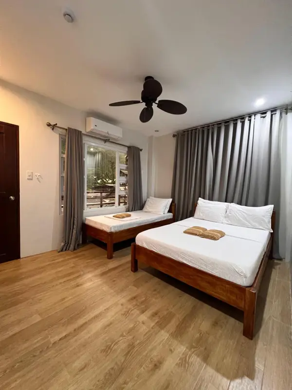 Une chambre lumineuse avec deux lits simples et un grand lit double.