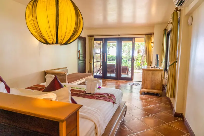 Une chambre lumineuse avec un lit décoré et un accès à une terrasse.