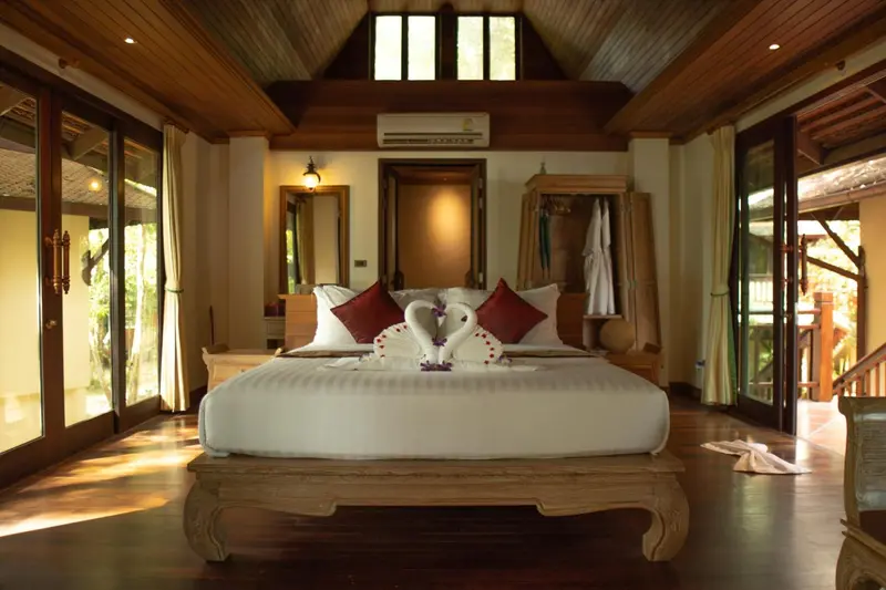 Une chambre lumineuse avec un grand lit recouvert de draps blancs et décoré de serviettes en forme de cygnes.