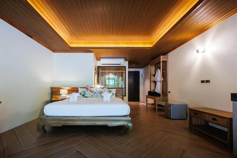 Une chambre lumineuse avec un grand lit et un parquet en bois.