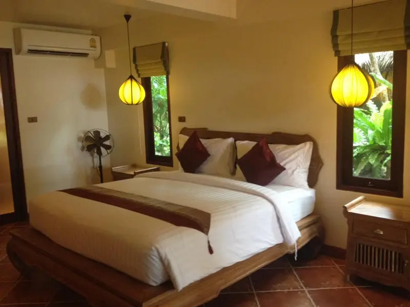 Une chambre lumineuse avec un grand lit et des luminaires suspendus.