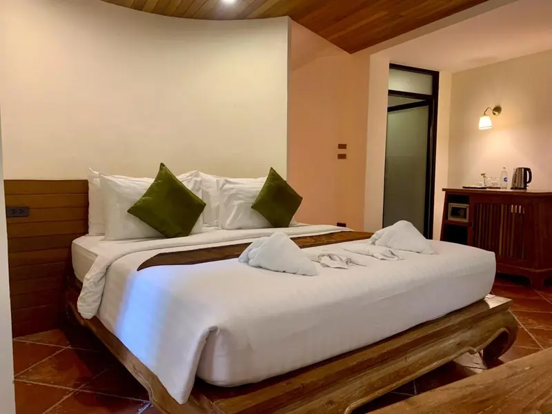Une chambre lumineuse avec un grand lit recouvert de draps blancs et de coussins verts.