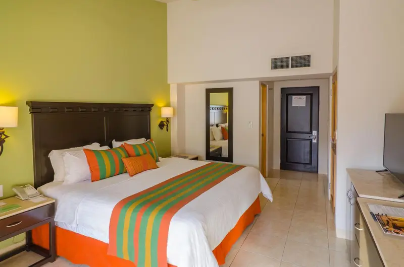 Une chambre lumineuse avec un grand lit recouvert d'une courtepointe colorée.