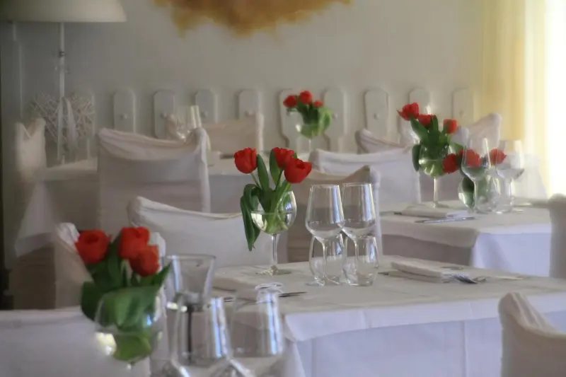 Tables dressées avec des fleurs rouges dans un restaurant clair.