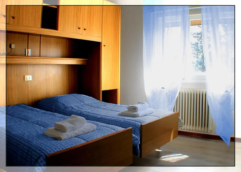 Une chambre avec deux lits simples et une armoire en bois.