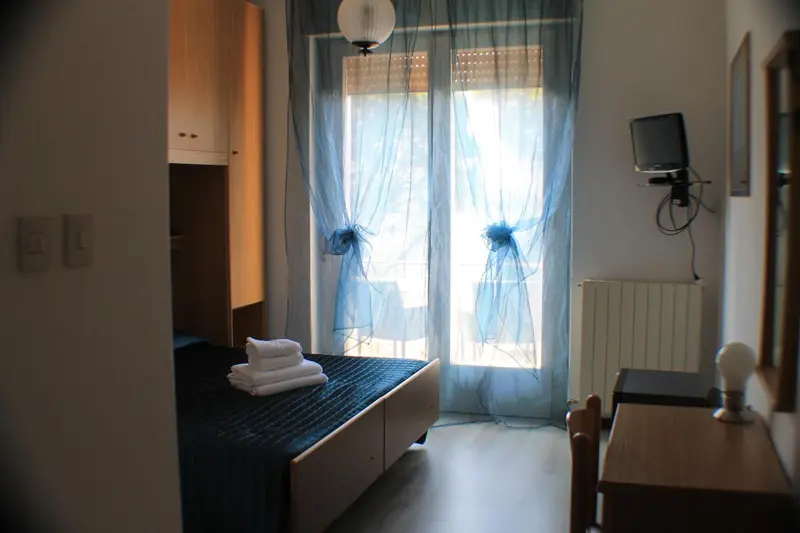 Une chambre lumineuse avec un lit et un accès à une terrasse.