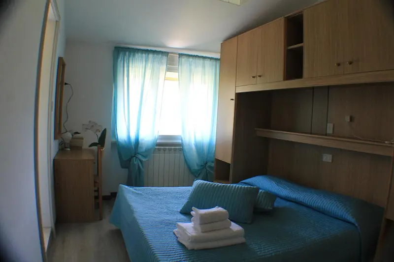 Une chambre lumineuse avec un lit fait et un bureau.