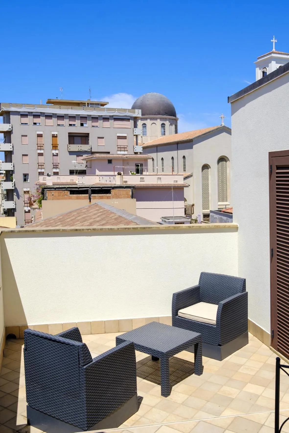 Terrasse aménagée avec mobilier en résine tressée et vue sur des bâtiments.