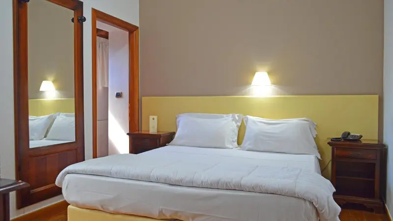 Une chambre lumineuse avec un grand lit et un miroir.