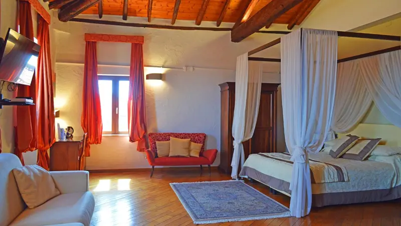 Une chambre lumineuse avec un lit à baldaquin et un canapé.