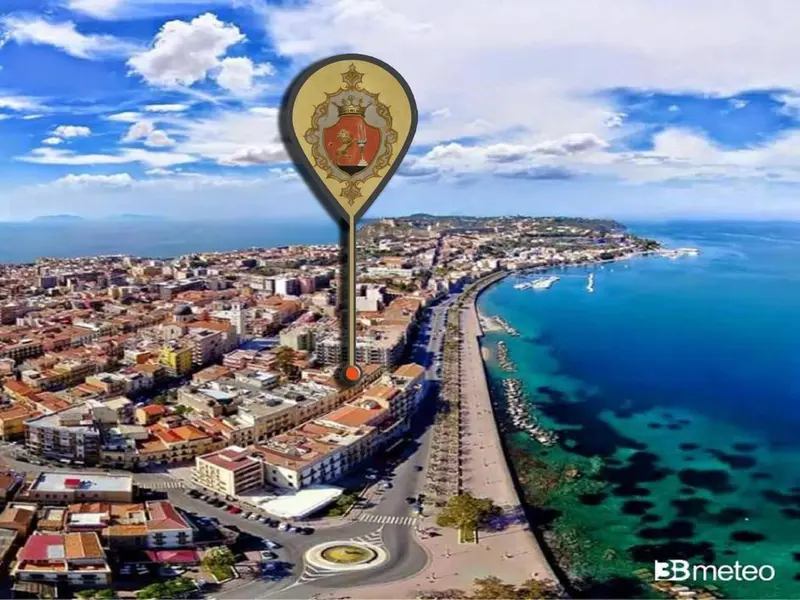 Vue aérienne d'une ville côtière avec une promenade en bord de mer et des bâtiments colorés.