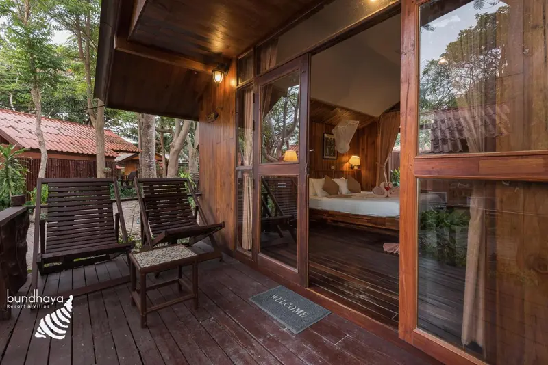 Terrasse en bois avec deux fauteuils et une vue sur une chambre.