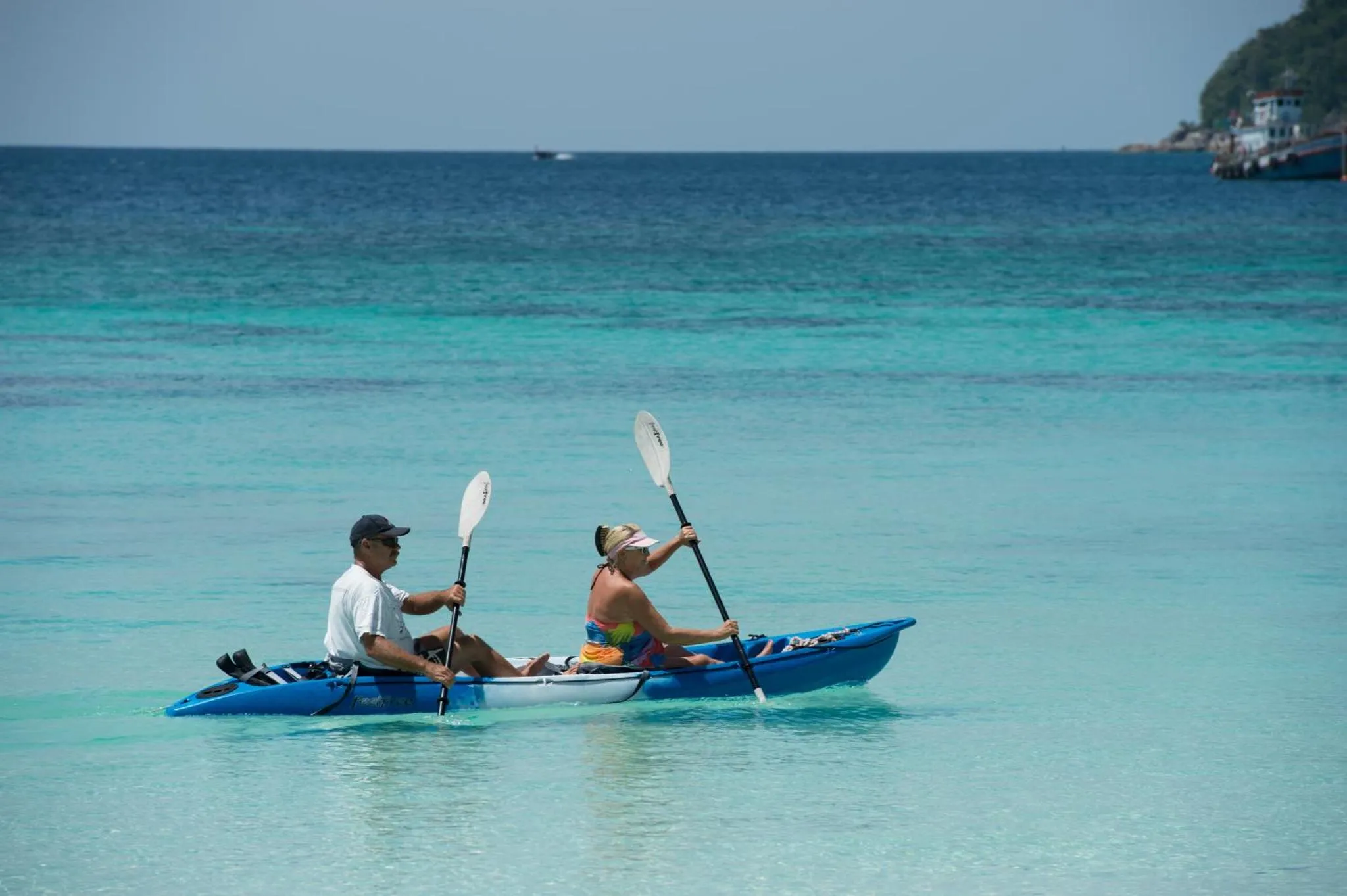 Deux personnes pagayent en kayak sur une eau turquoise et calme.