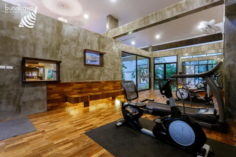 Une salle de sport lumineuse avec des équipements de fitness et un parquet en bois.