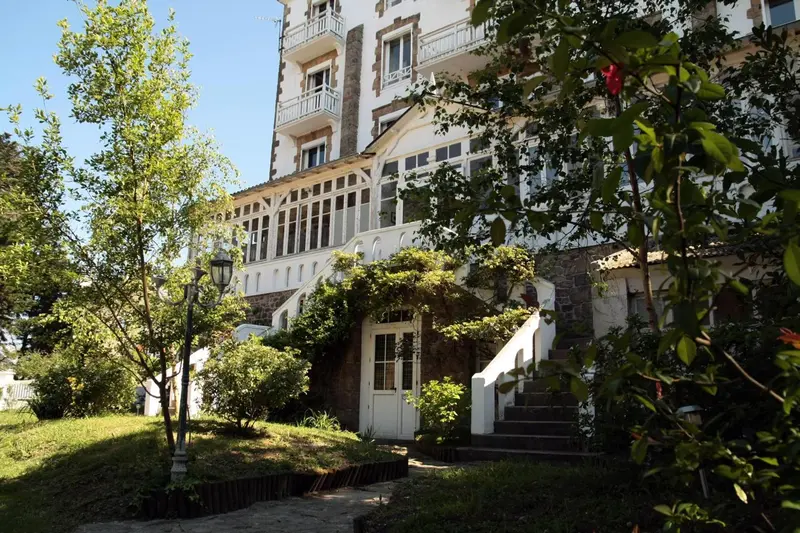 Façade d'un bâtiment blanc avec des balcons et une végétation luxuriante.