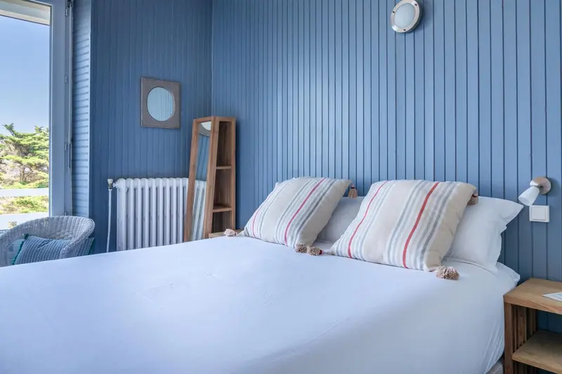 Une chambre lumineuse avec un lit recouvert d'une courtepointe rayée et une vue sur la mer.