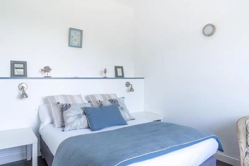 Une chambre lumineuse avec un lit recouvert d'une courtepointe et de coussins.