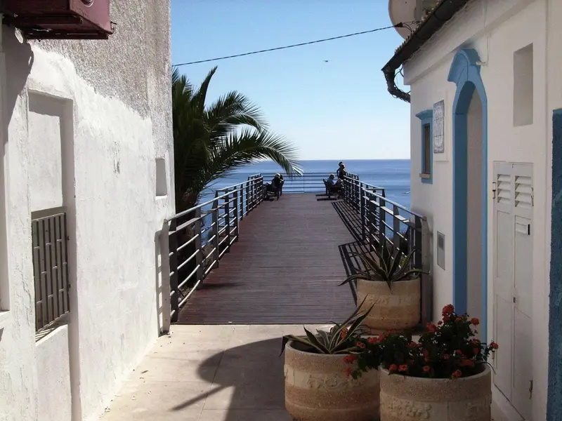 Une allée mène à une promenade en bois avec vue sur la mer.