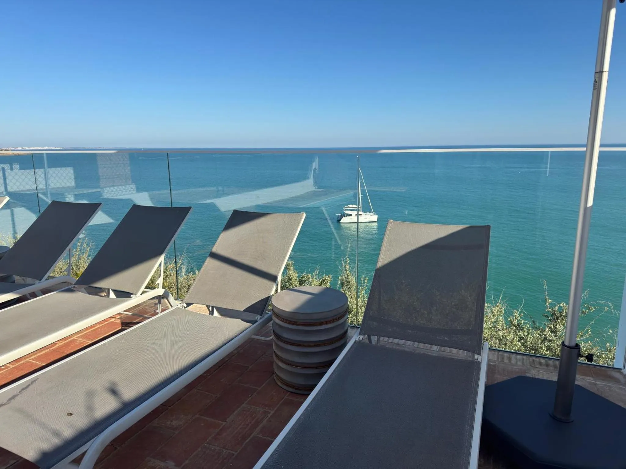 Transats et parasols sur une terrasse surplombant la mer turquoise.