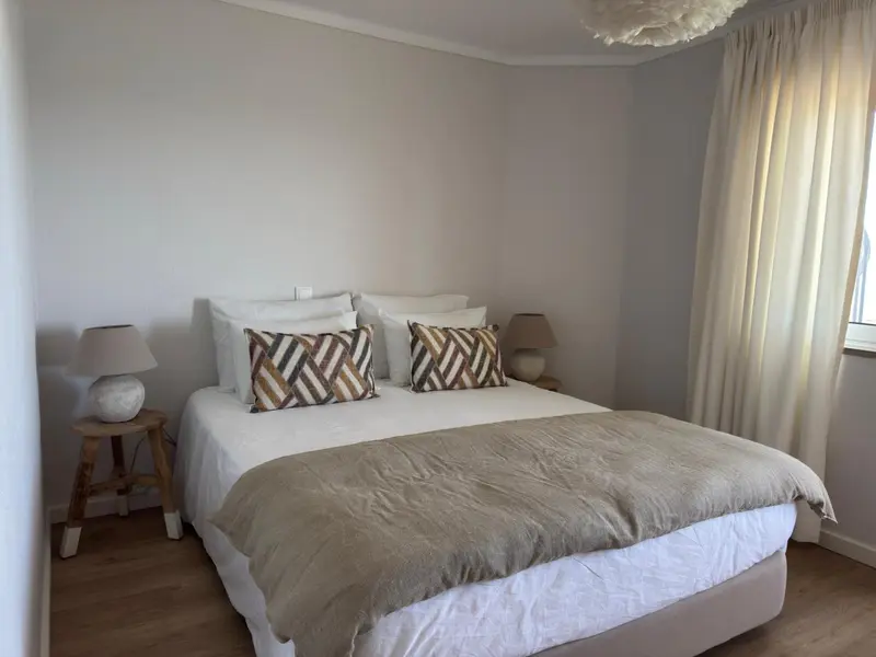 Une chambre lumineuse avec un grand lit recouvert d'une courtepointe.