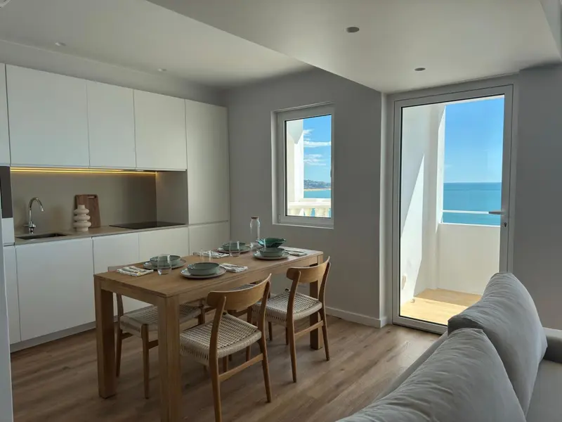 Une cuisine moderne s'ouvre sur une salle à manger et une terrasse avec vue sur la mer.
