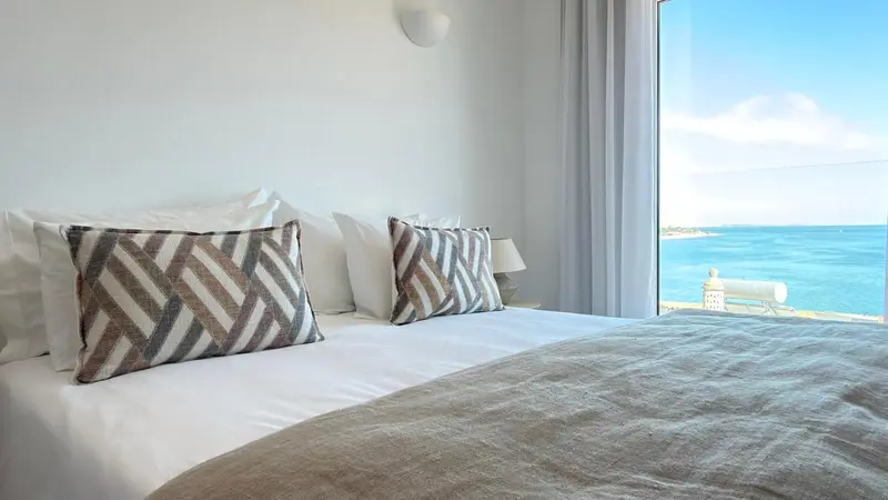 Une chambre lumineuse avec un grand lit et vue sur la mer.