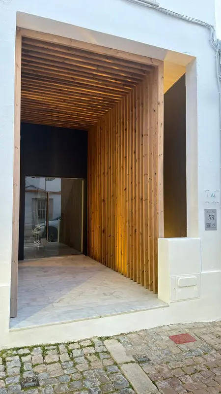 Entree d'un batiment avec une facade en bois et un sol pave.