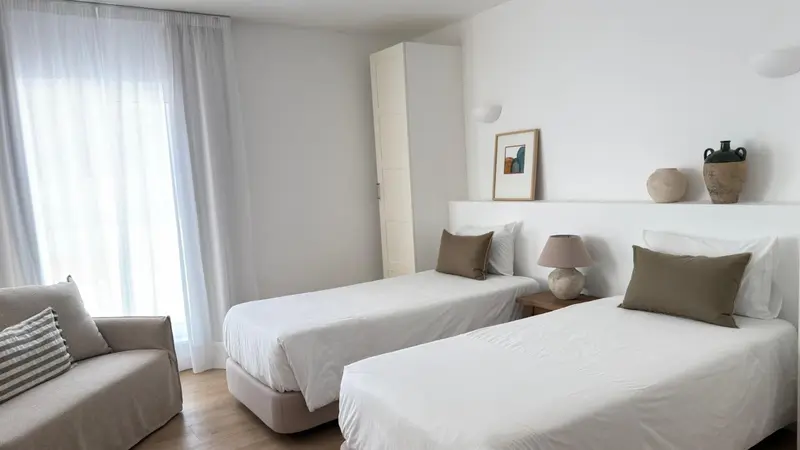 Une chambre lumineuse avec deux lits simples et un coin salon.
