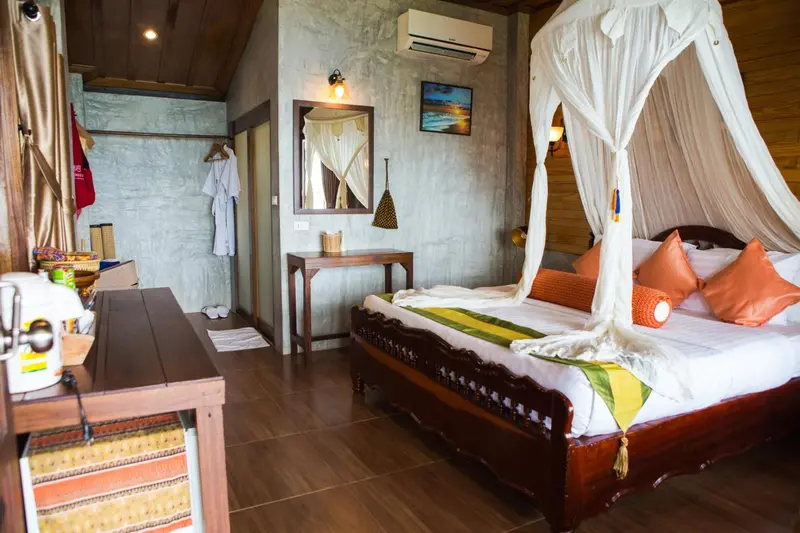 Une chambre avec un grand lit à baldaquin et un coin repos.