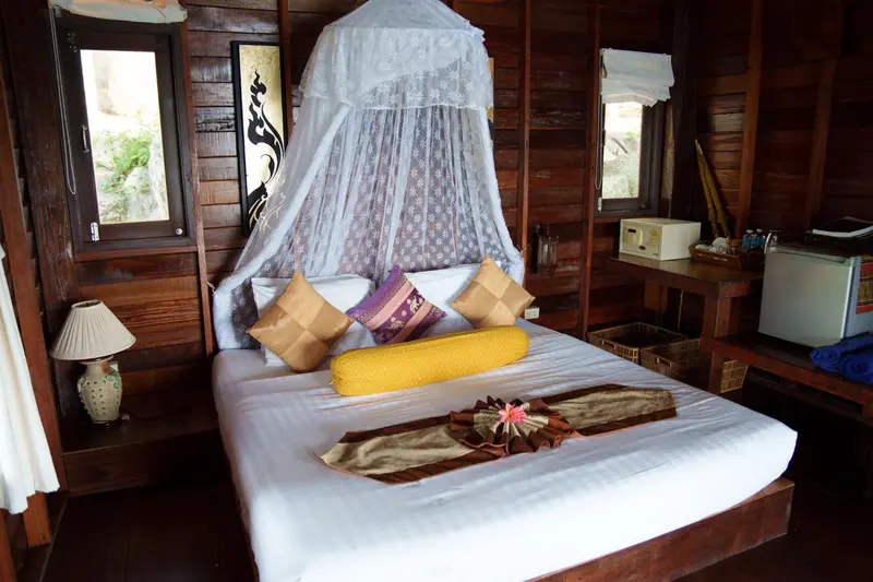 Une chambre avec un lit recouvert d'une moustiquaire et de coussins.