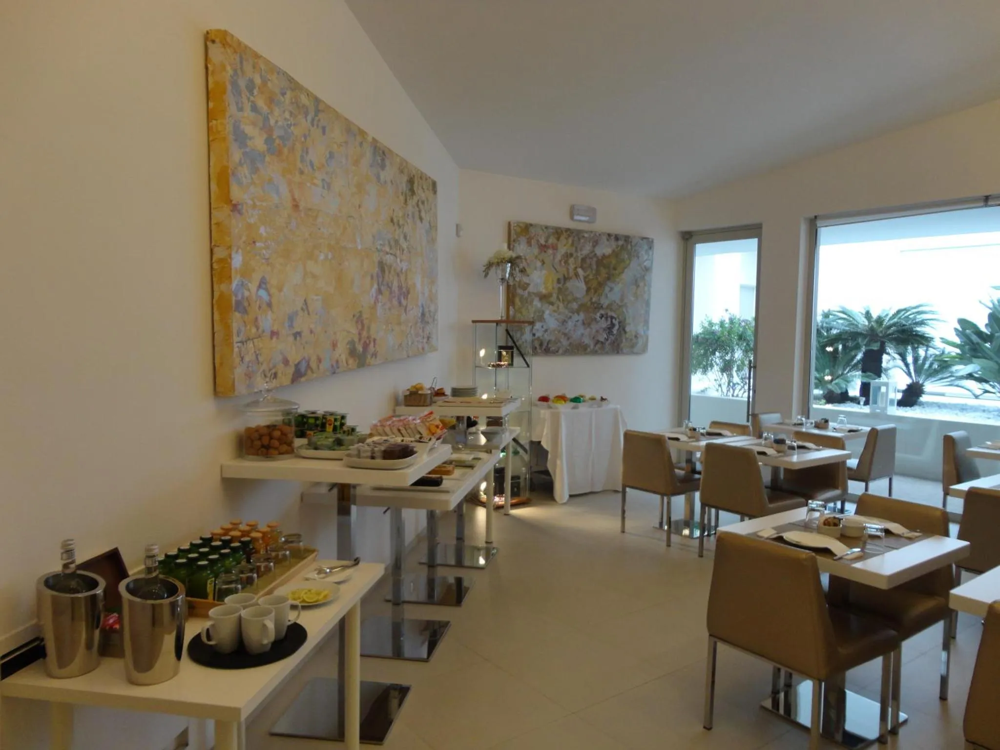 Une salle lumineuse avec un buffet et des tables à manger près d'une baie vitrée.