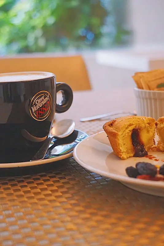 Une tasse de café et une pâtisserie sont présentées sur une table.
