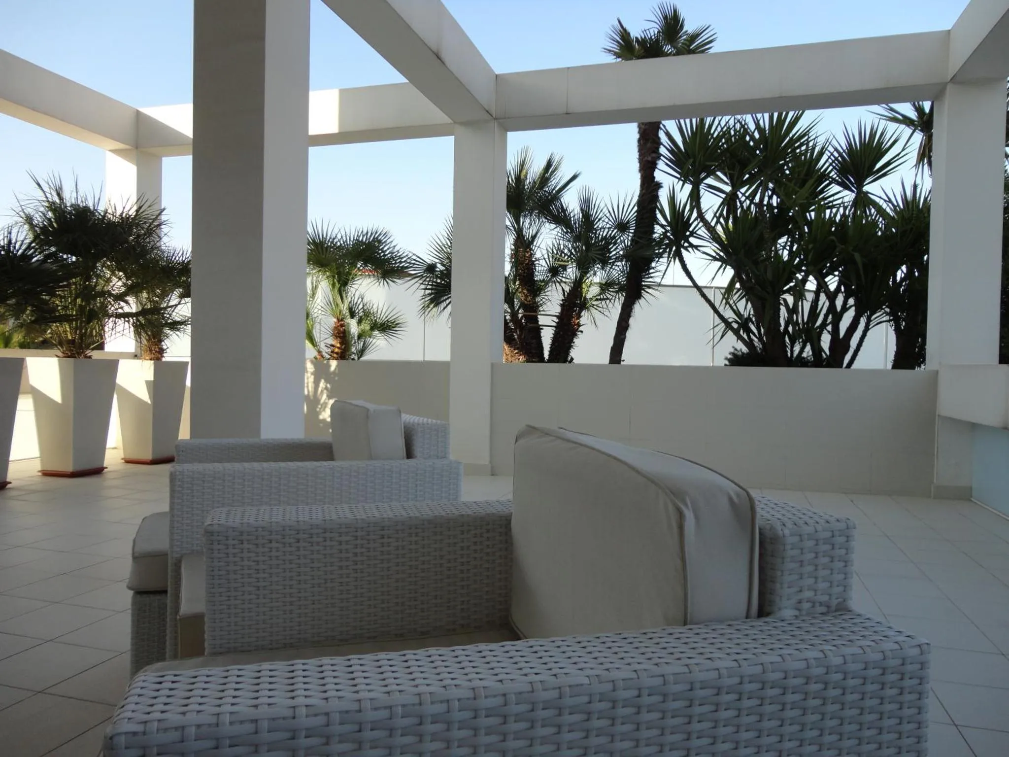 Espace de détente extérieur avec mobilier blanc et végétation tropicale.