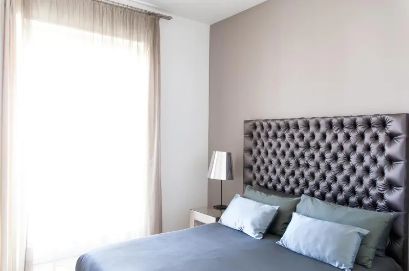 Une chambre avec un grand lit et une tête de lit capitonnée.