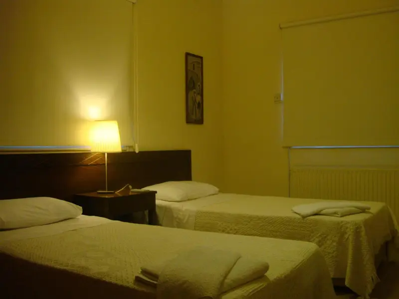 Une chambre lumineuse avec deux lits simples et une lampe de chevet.
