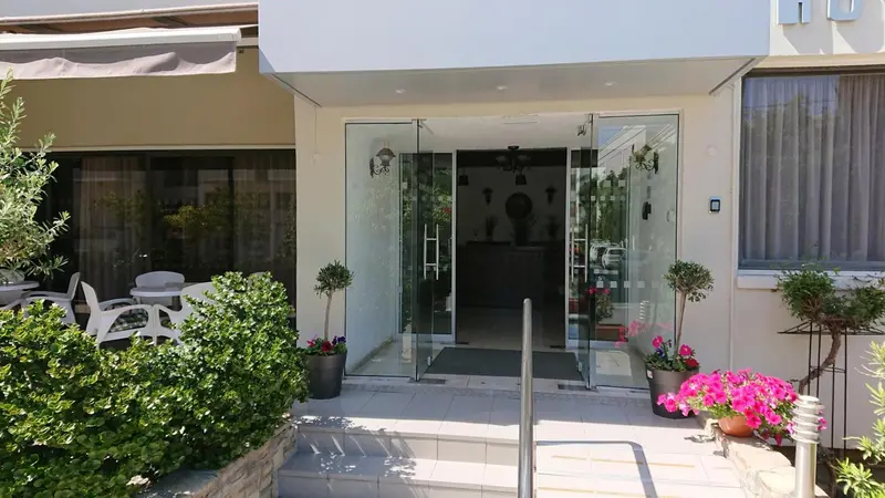 Entree d'un batiment blanc avec des plantes et des marches.