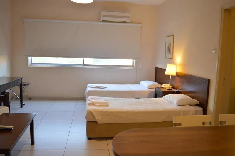 Une chambre lumineuse avec deux lits simples et un bureau.